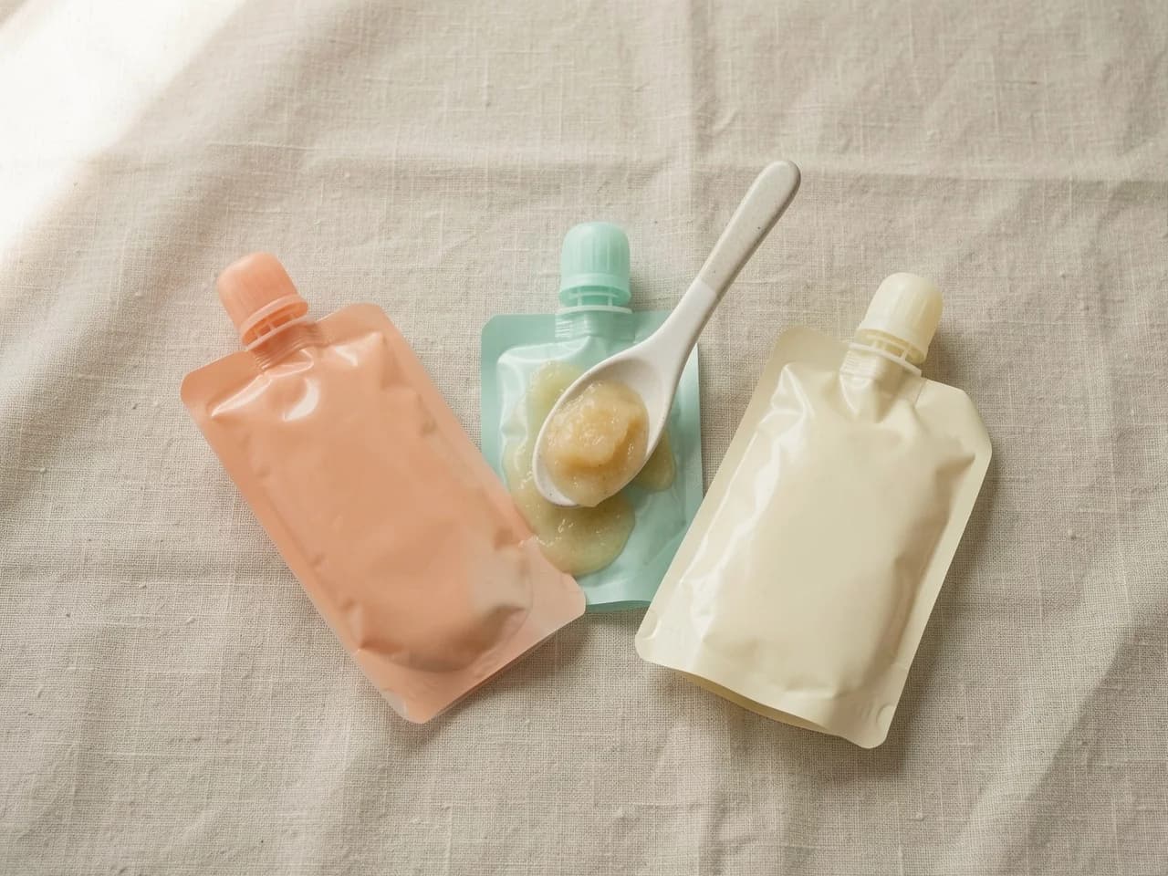 Een rij knijpbare babyhapjes-zakjes op een licht oppervlak, ter illustratie van de producten die getest zijn in het Greenpeace-onderzoek van mei 2026 dat duizenden microplasticdeeltjes per zakje vond
